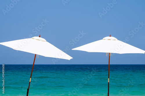 White beach umbrella on a sunny day against sea background.