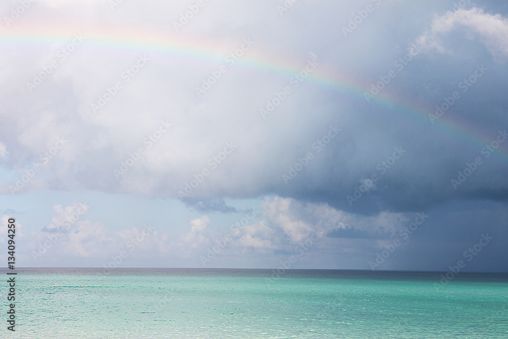 Морской пейзаж - яркое лазурное Карибское море, кучевые облака и радуга. Фото сделано на Кубе.