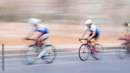 Blurred background of men riding bicycle.