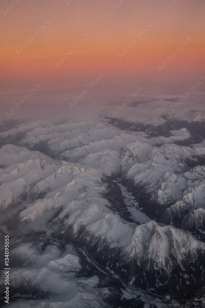 Fototapeta premium Aerial view of snowy mountains at sunset