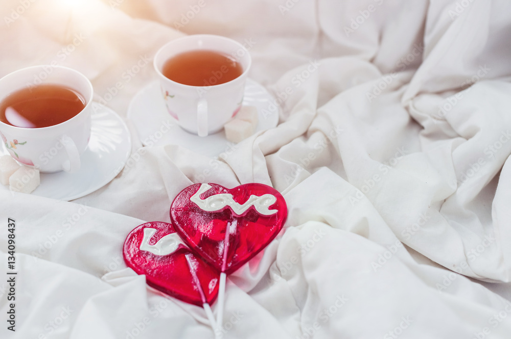 Breakfast in bed in Valentines day. Cup of tea and sweet candies. Love or holiday concept Breakfast in bed in Valentines day. Cup of tea and sweet candies. Love or holiday concept