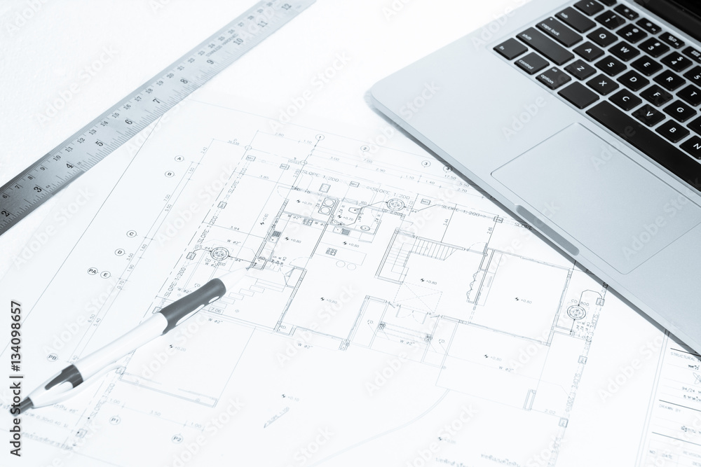 Pen, metal ruler, rubber and notebook over house construction bl Pen, metal ruler, rubber and notebook over house construction bl