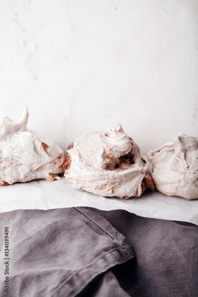 Homemade french meringue on white baking paper with gray towel Homemade french meringue on white baking paper with gray towel