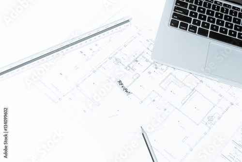 Pen, drawing rulers, and notebook over house construction bluepr