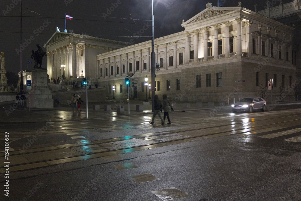 Night view of Vienna Parliament lighted, with green traffic jam