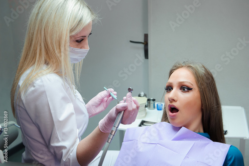 Frightened woman sitting in the dentist s chair while studying t
