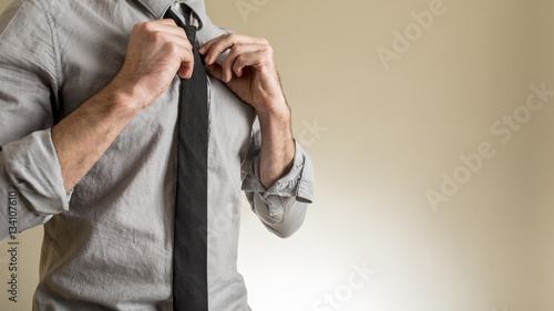 Man adjusting his black necktie © Gajus