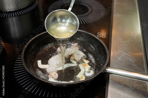 Chef is adding fish stock to seafood stew © Kondor83