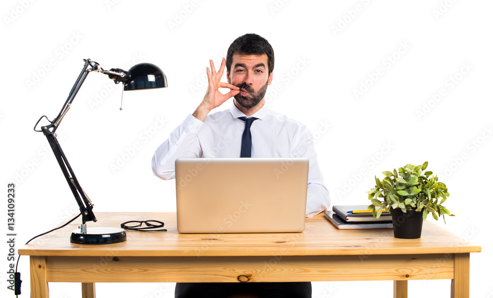 Businessman in his office making silence gesture Businessman in his office making silence gesture