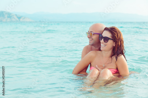 Cheerful couple embracing and posing in the water sea on a sunny