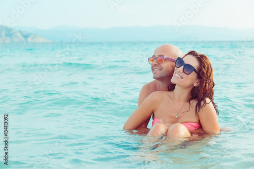 Cheerful couple embracing and posing in the water sea on a sunny © hbrh