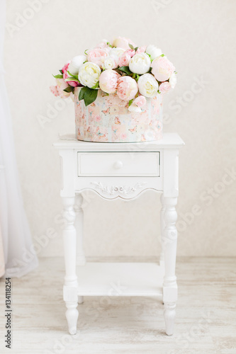 Circkle box full of peony flowers on a white wooden table photo