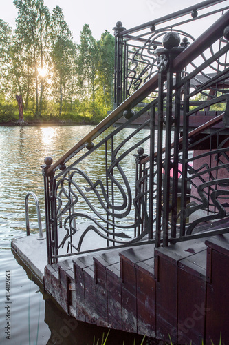 Pond with wooden pier and details of metal forged fence, close up
 photo