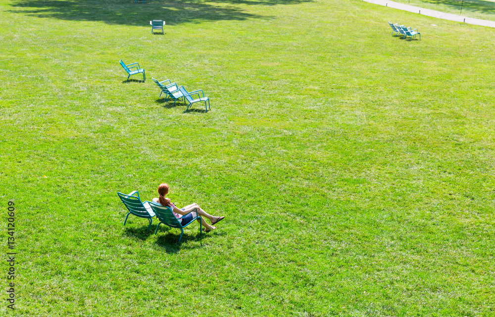 Woman sitting on armchair in the middle of meadow. Woman sitting on armchair in the middle of meadow.