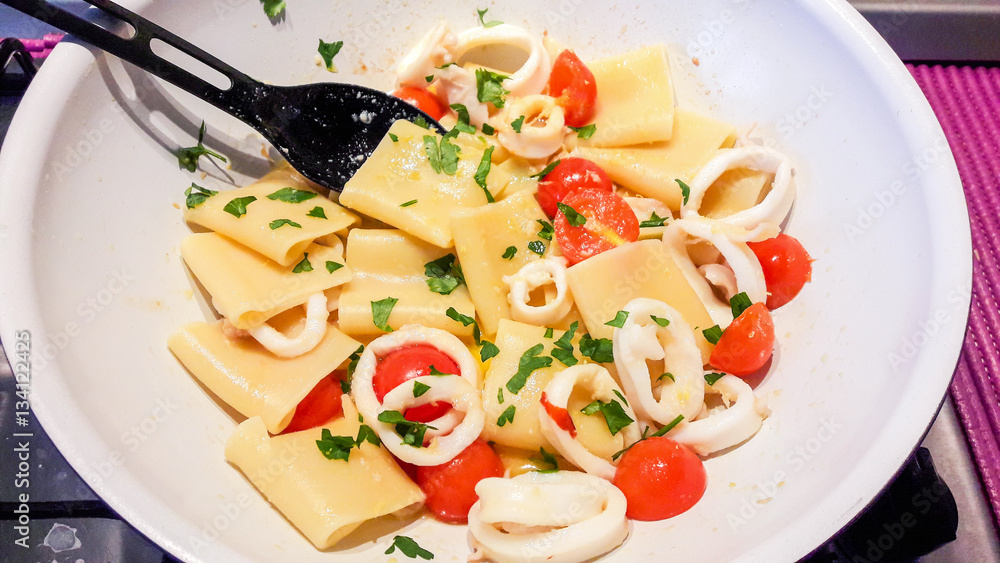 Paccheri, Italian pasta with squid sauce, small tomatoes, garlic, chili, parsley, and grated lemon Paccheri, Italian pasta with squid sauce, small tomatoes, garlic, chili, parsley, and grated lemon