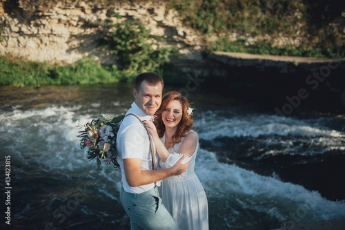 the bride and groom on the background of a mountain stream