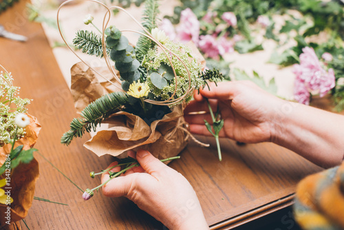 Woman's hands making flower composition at floristic workshop, DIY tools, branches. stems and twine for creative work