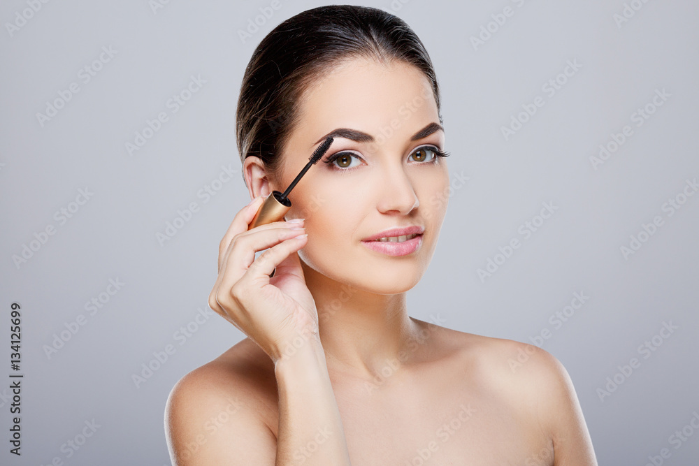 Model painting eyelashes with mascara