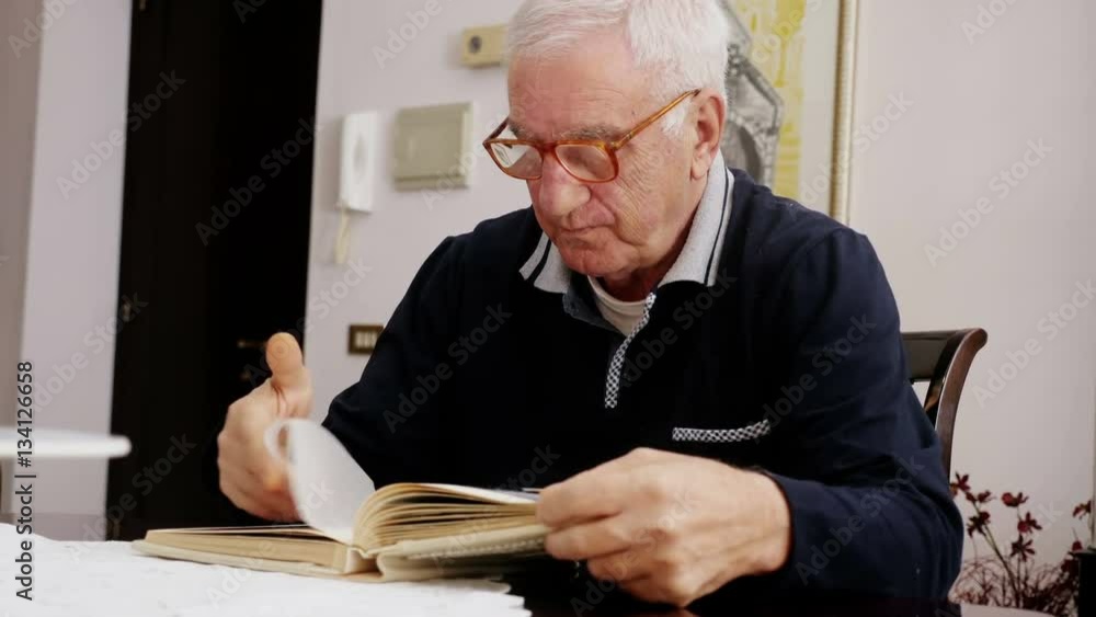 grandfather sitting at his desk leafing through an old photo album grandfather sitting at his desk leafing through an old photo album
