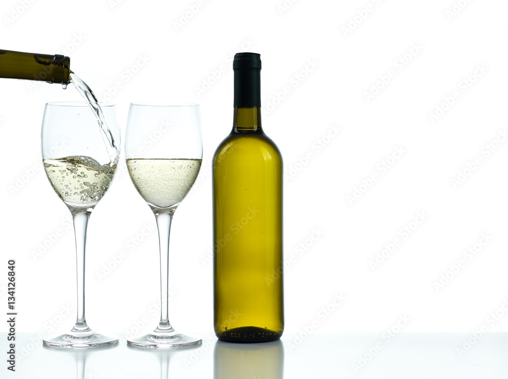 Bottle and glasses of white wine on a white background. Wine poured in one glass from a bottle. Bottle and glasses of white wine on a white background. Wine poured in one glass from a bottle.