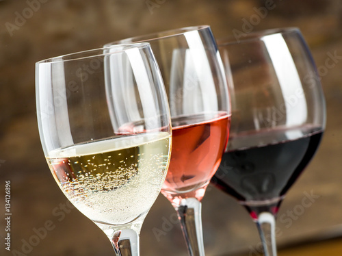 Glasses of red, white and rose wine on a dark wood background