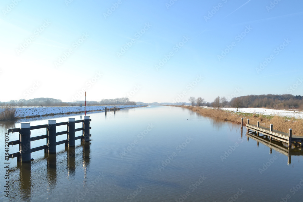 het zonnetje schijnt op een winterdag op een besneeuwde rivier de Oude IJssel bij Hoog Keppel