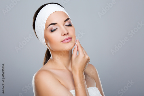Woman with white headband touching face