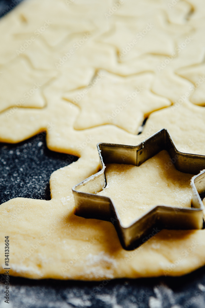 Metal star-shaped form placed in cookie dough.