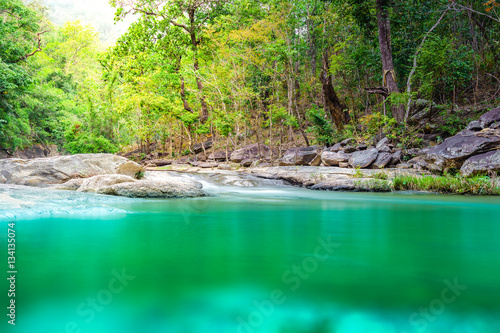 Beautiful waterfall streamlet with a green nature forest and sun