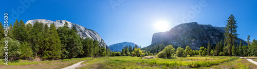 Meadow and trees surrounded by rocky mountains photo