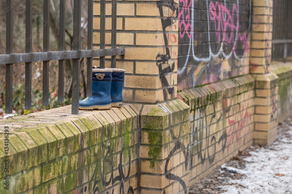 Naklejka premium Kinderstiefel auf einer Backsteinmauer