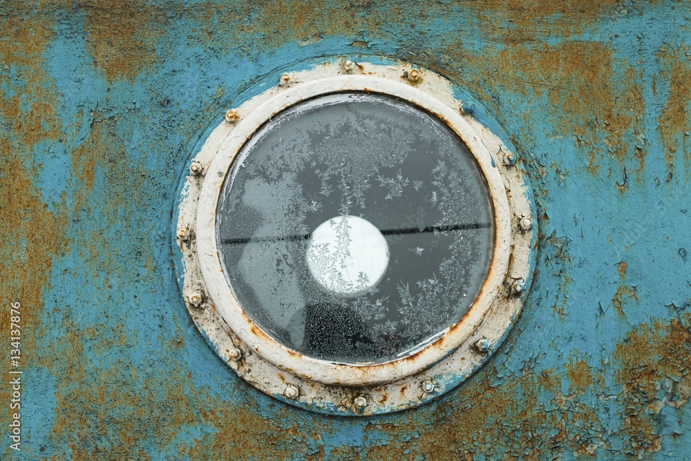 Porthole on the blue wall of the old ship. Stock image.