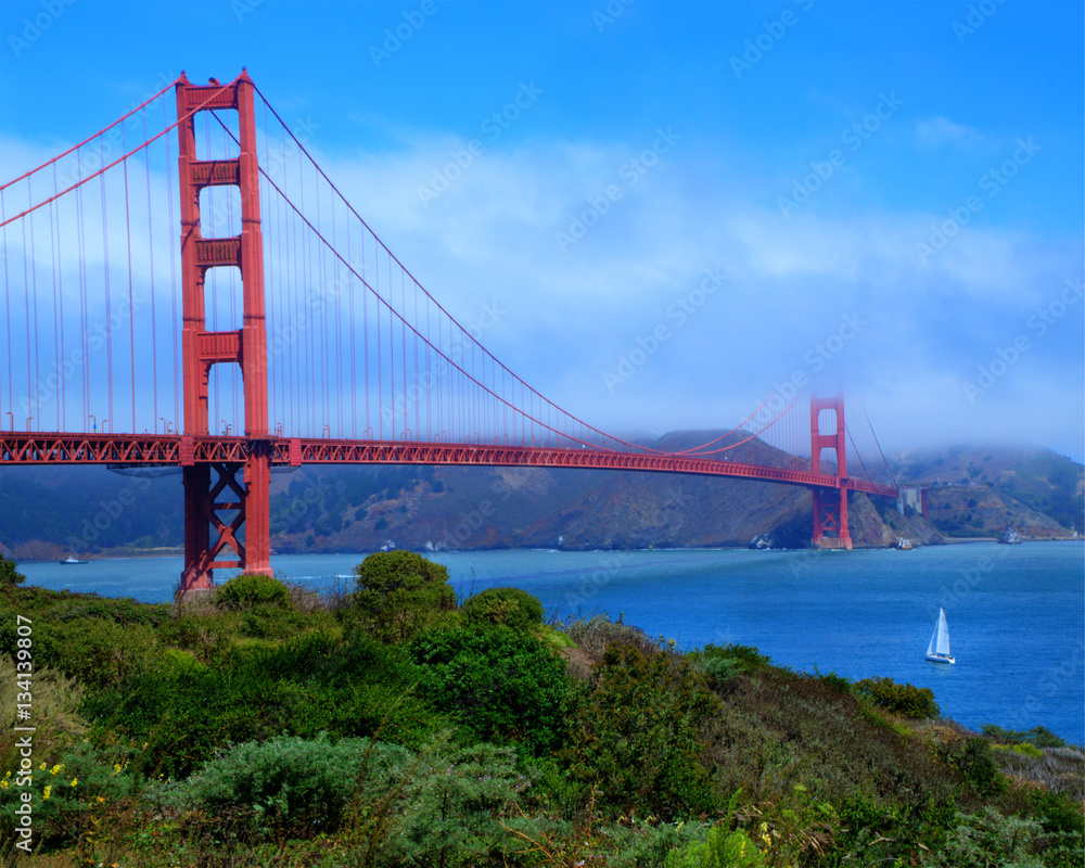 The Golden Gate Bridge on an early morning with a layer of fog and clouds still rolling in across the bay The Golden Gate Bridge on an early morning with a layer of fog and clouds still rolling in across the bay