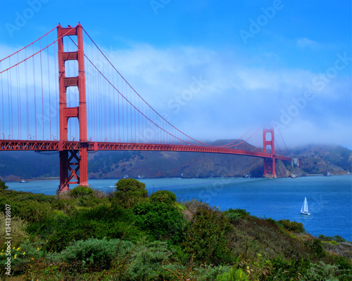 The Golden Gate Bridge on an early morning with a layer of fog and clouds still rolling in across the bay