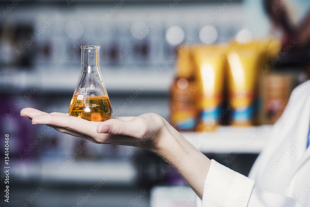close up of a female hand, pharmacist is holding a test tube filled with chemical ingredient