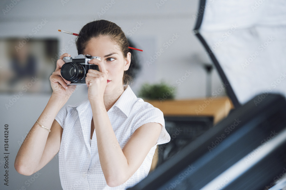Beautiful woman photography professional is working in the photography studio, taking a picture using her camera