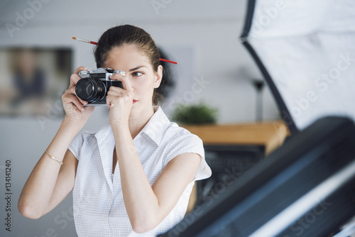 Beautiful woman photography professional is working in the photography studio, taking a picture using her camera © PhotoPlus+