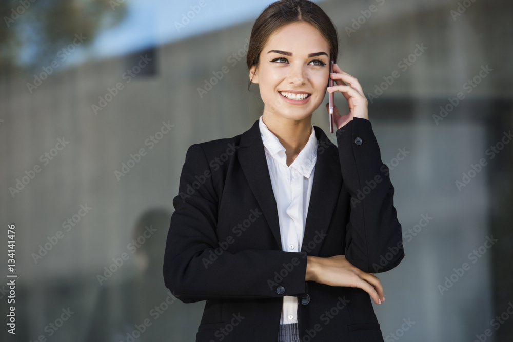 Beautiful young businesswoman is talking on her smart phone device, looking up and smiling. With copy space. Beautiful young businesswoman is talking on her smart phone device, looking up and smiling. With copy space.
