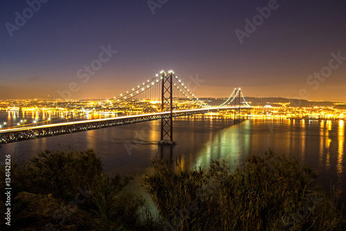 Sonnenuntergang hinter der Ponte 25 de Abril, die Brücke über den Tejo in Lissabon ( mit Industriehafen im Vordergrund)