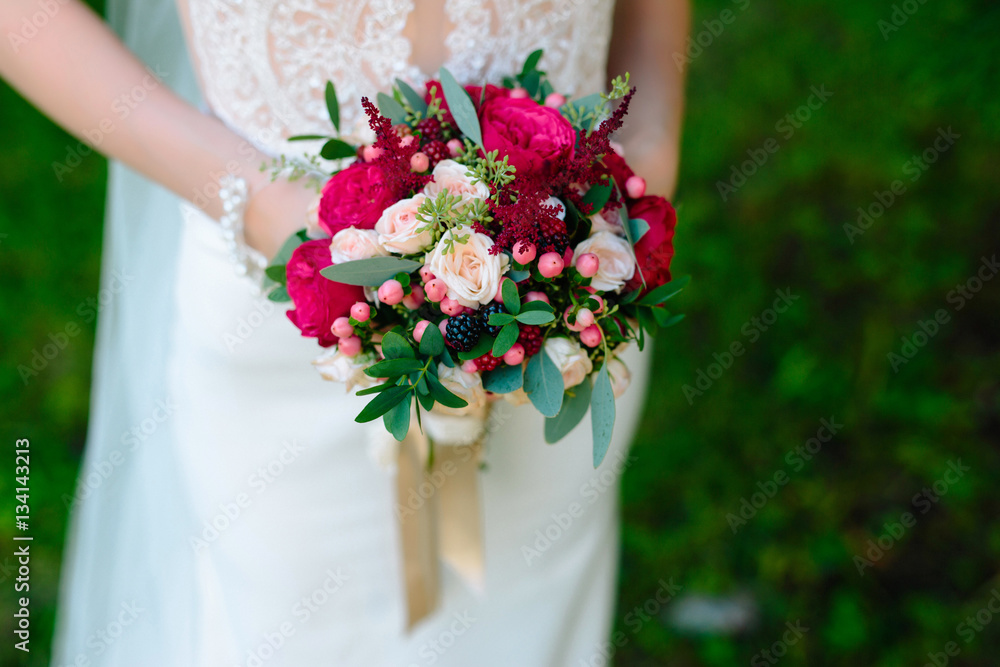 bride holding bouquet of roses, berries and green sprigs bride holding bouquet of roses, berries and green sprigs