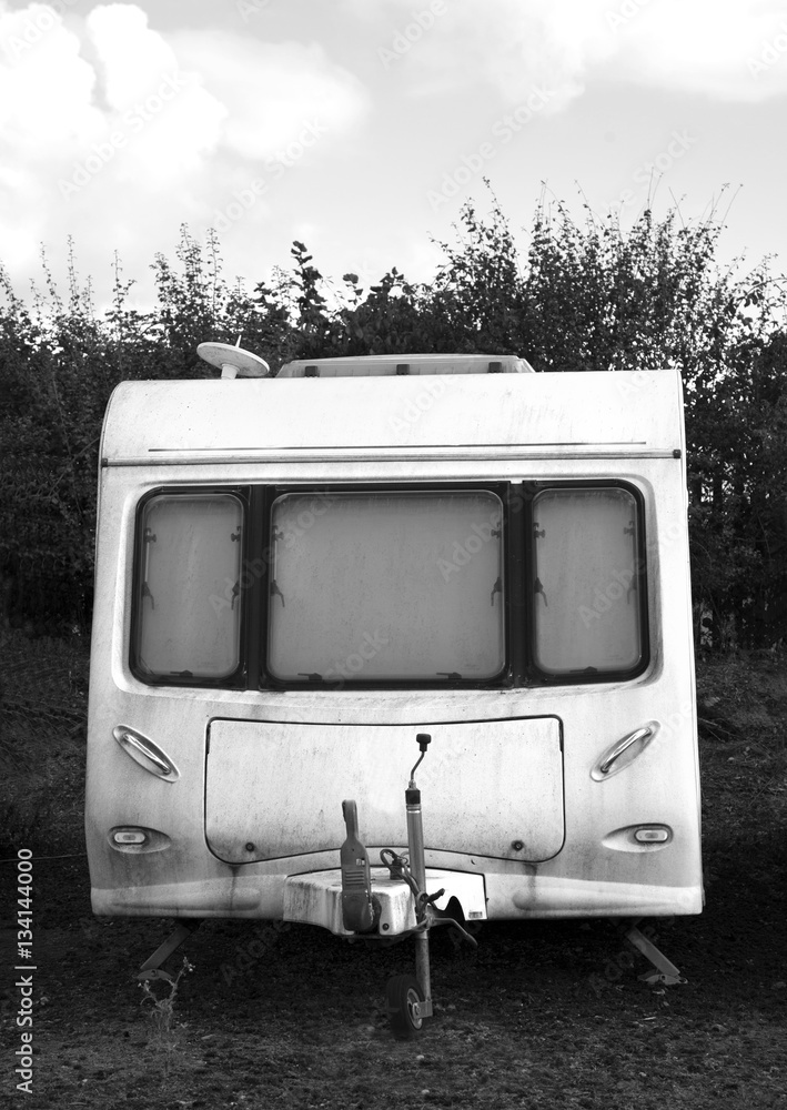 Black and white rundown dirty old caravan on a sunny day with clouds in the sky. Space for text. Black and white rundown dirty old caravan on a sunny day with clouds in the sky. Space for text.