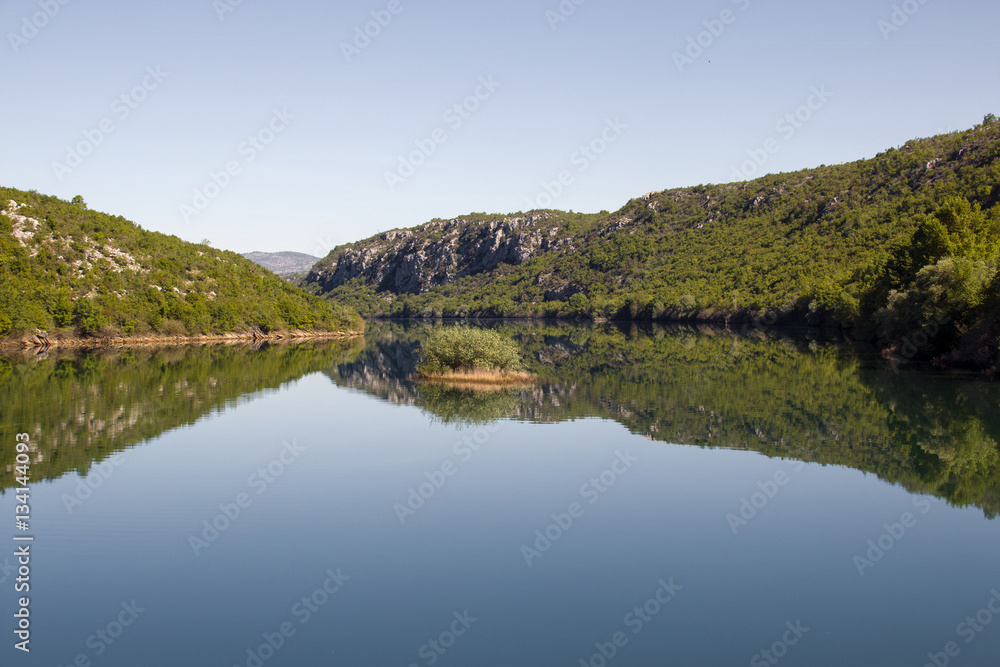 Reflection in turquoise blue water of artificial lake Prancevic on the river Cetina in Croatia