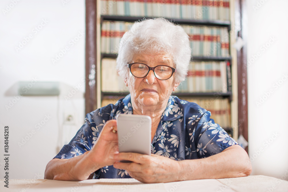 Elderly woman looking at a smart phone at home. Elderly woman looking at a smart phone at home.