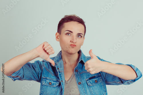 Thumb up or thumb down. Skeptical thinking woman judging deciding how to rate a situation. Is it good like or bad dislike concept Human emotion body language face expression. Horizontal image studio