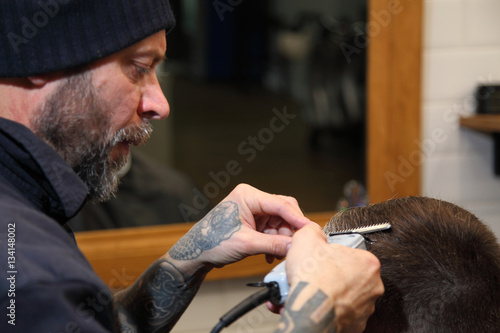 Barber cuts the hair of the client with clipper at barbershop.