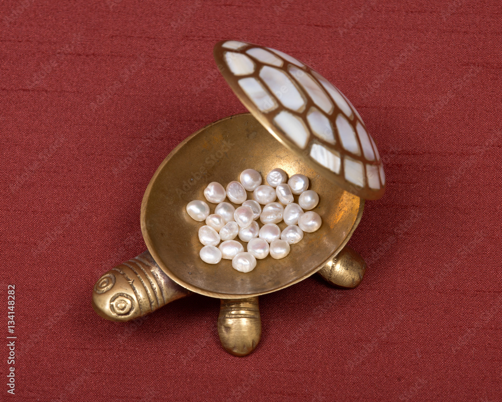 Decorative turtle jewelry box and freshwater white beads of pearl on red fabric backboard Decorative turtle jewelry box and freshwater white beads of pearl on red fabric backboard