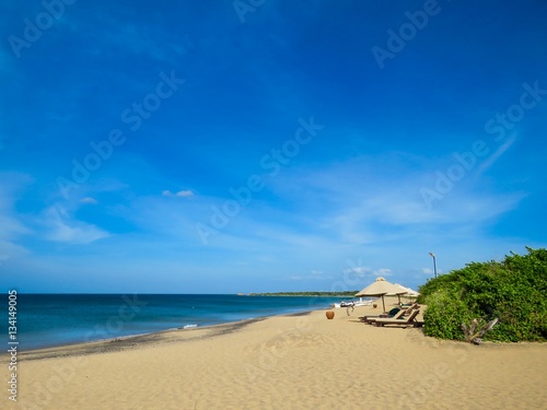 Sunbed Sun umbrella on Relaxing White Sand sandy beach with greenery and blue sky with clouds 