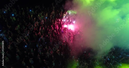 Aerial view of crowd with red signal flare dancing on music festival