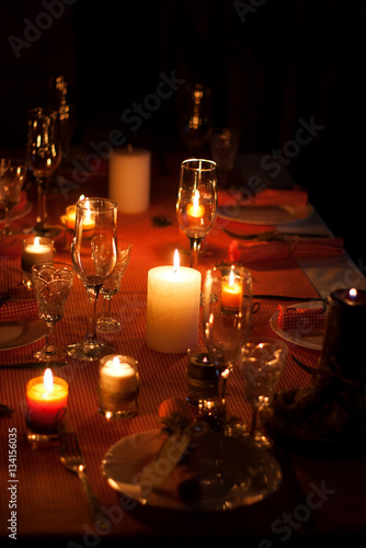 Festive composition with candles and plates. Table decoration. A beautiful table setting, red table cloth, tablecloth in a cage. Christmas dinner. A white plate with a nice napkin on the table