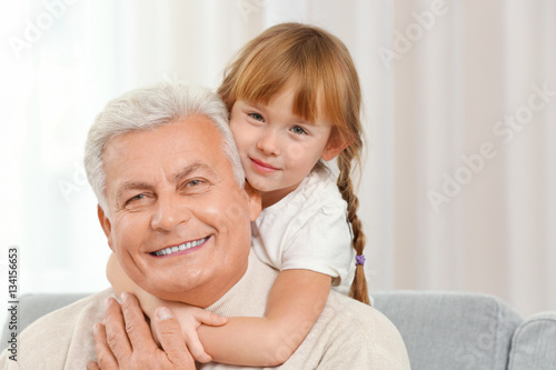 Happy grandfather with granddaughter on couch